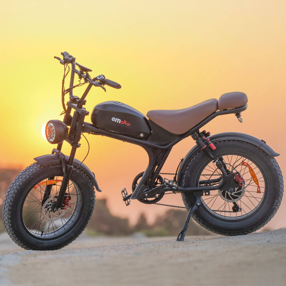 Emoko off-road fat tire electric bicycle in black with brown seat parked at sunset on a dirt path