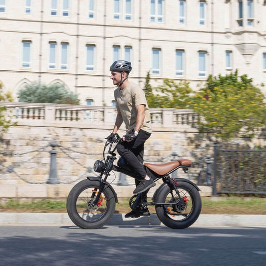 Man riding Emoko off-road fat tire electric bicycle on city street with safety helmet
